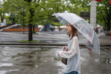 雨の公園を歩く女性