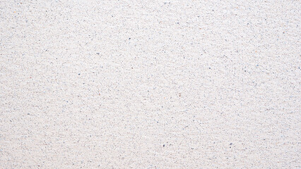 A white wall with a pattern of small dots. The wall is plain and unadorned. The dots are evenly spaced and cover the entire surface of the wall. The wall appears to be made of a smooth