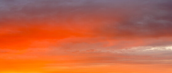 A beautiful sunset with a red and blue sky. The sky is filled with clouds and the sun is setting