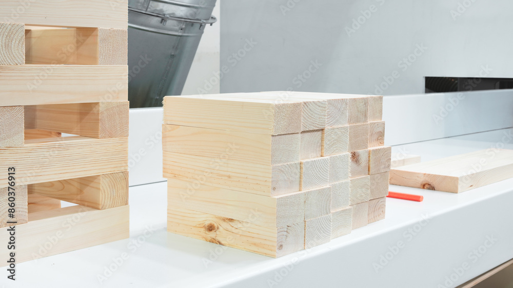 Poster A white counter top with a stack of wooden blocks on it. The blocks are of different sizes and are arranged in a way that they look like a puzzle. Concept of creativity and playfulness