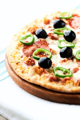 Pizza with salami, jalapeno pepper and black olives. Home made food. Concept for a tasty and hearty meal. Close up.	