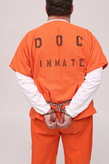 männlicher Strafgefangene in Handschellen mit Bauchkette und orangen Overalls, Rückenansicht