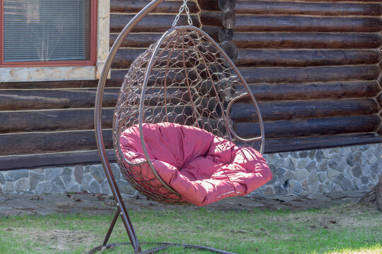 Hanging garden chair for relaxing in a country yard near the wall of the house.
