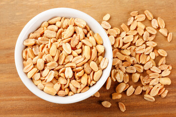 Roasted peeled peanuts in bowl on wooden table