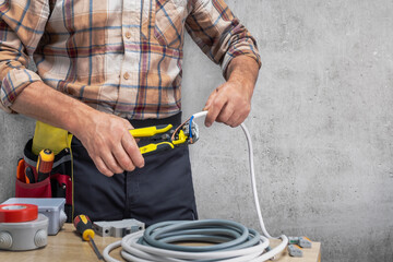  electrician cleans the protective insulation from the wire using a wire stripper.