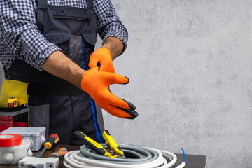 Professional electrician technician in uniform putting protective gloves.