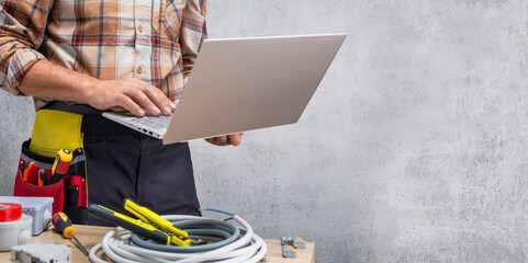 electrician in uniform using laptop. banner with copy space.