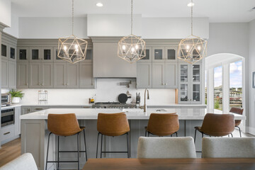 High end luxury kitchen with gray cabinets, white stone countertops and designer pendant lights 