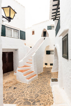 The beautiful town of Binibeca on Menorca. Narrow streets and white walls of houses with wooden elements, Mediterranean architecture in Spain