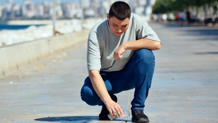 Young man picking up the garbage he saw on the ground