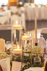 Soft lit candles in glass vases with flowers