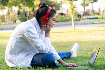 Fototapeta premium Young beautiful Asian woman working with laptop/internet/online shopping at outdoor park,