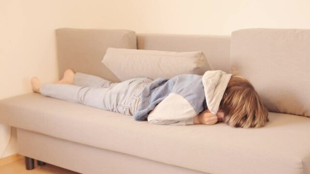 12-year-old boy in frustration, lying on sofa, punching pillows, experiencing teenage angst and tantrums, coping with emotions, angst and frustration, mental health