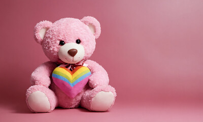 Pink teddy bear holding rainbow heart on pink background