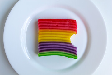 Bitten Kue Lapis, layered jelly in rainbow colors. Kue Lapis is traditional snack from Indonesia. Isolated on white background, flat lay or top view