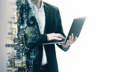 Headless young businessman using laptop on abstract blurry white city background with mock up...