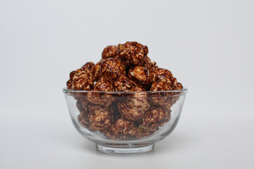 Chocolate popcorn, in transparent glass bowl, isolated on white background