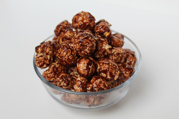 Chocolate popcorn, in transparent glass bowl, isolated on white background