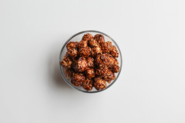 Chocolate popcorn, in transparent glass bowl, isolated on white background, flat lay or top view