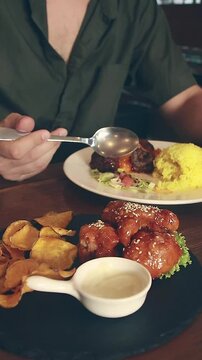 Candid scene of enjoying eating a full creative vegan meal of glazed battered cauliflower, java rice and falafel frikadelle, healthy sustainable lifestyle 
