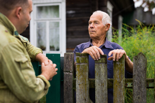 Farm neighbors talk at the border of garden plot