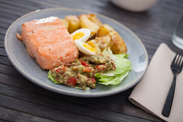 Baked salmon fillet with fried potato wedges, homemade guacamole and quail eggs halves