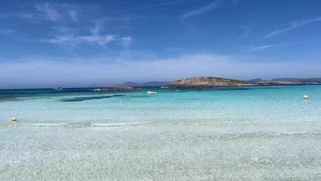 White sand beach on a narrow strip of land on Formentera. Blue famous beach with people relaxing on vacation in the mediterranean sea with luxury vessels and boats. Turquoise sea.