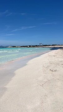 Vertical video. White sand beach on a narrow strip of land on Formentera. Blue famous beach with people relaxing on vacation in the mediterranean sea with luxury vessels and boats. Turquoise sea.
