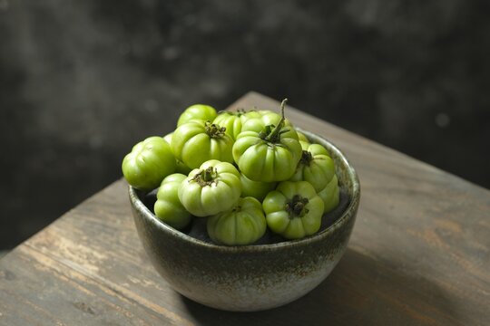 Pile of green tomatoes or Solanum Lycopersicum on the table with dark background. Tomat hijau