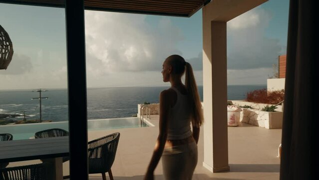 Woman Opens Sliding Door and Steps Out to Oceanfront Terrace