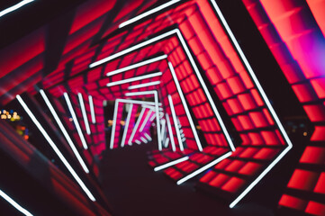 Futuristic neon tunnel with geometric abstract blur background . Vibrant red backdrop contrasts with white LED lines forming angular shapes. 
