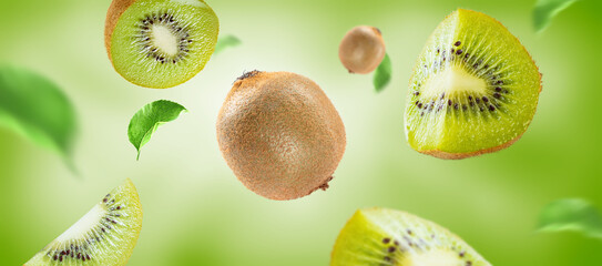 Fototapeta premium kiwi fruit with slices and leaves flying on green background