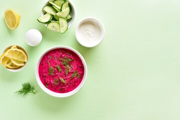 Cold summer beetroot soup in bowl over green background