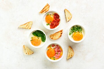 Eggs en cocotte (baked eggs) in portion ceramic bowls and toasts