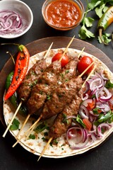 Lula kebab with fresh vegetables on flat bread on wooden platter