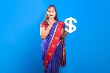 with a surprise facial expression women showing dollar sign standing against blue background