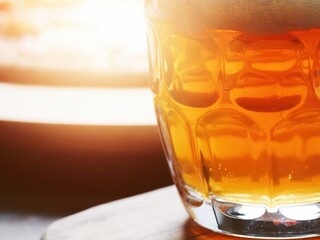 A glass of lager beer in focus. Italian cooked pizza out of focus in the background. Light and airy look.