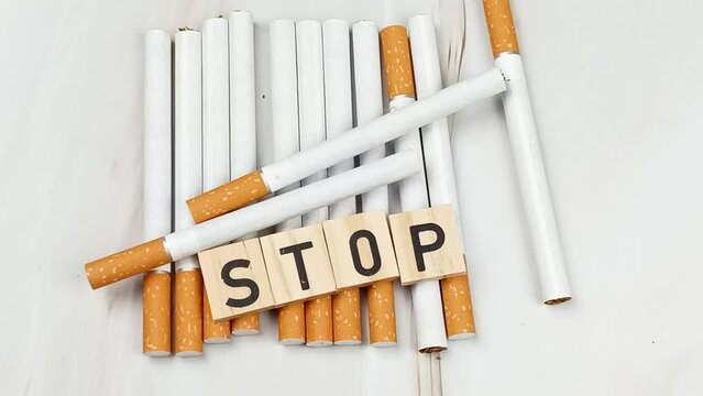 tas de cigarettes, vue du dessus, avec le mot Stop &eacute;crit en lettres en bois dessus.
