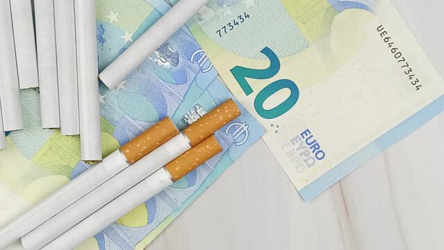 plusieurs cigarettes et billets de vingt euros, en gros plan, vue du dessus.