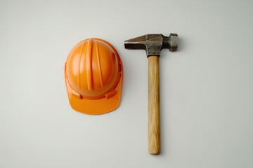 An orange hard hat and a hammer are lying on white surface,symbolizing Labor Day.This image represents dedication,hard work of laborers across various industries,highlighting the tools of their trade