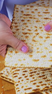 A Jewish woman breaks matzah at a laid Pesach Seder table