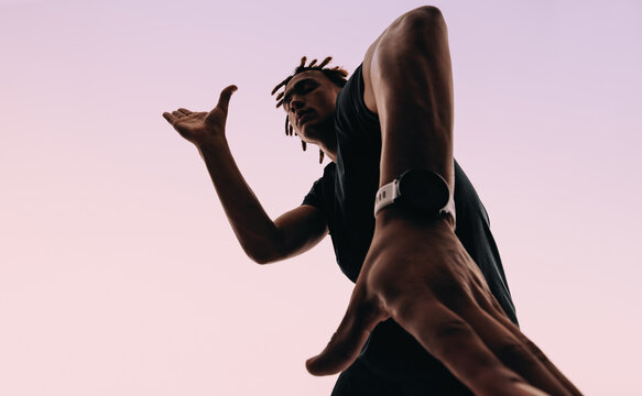 Expressive gen z dancing to music with earbuds and smartwatch in a pink silhouette studio