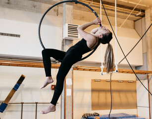 Woman performing acrobatic exercise on aerial hoop in studio