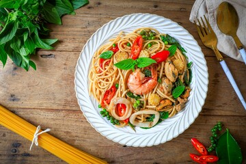 Stir Fried Spicy Spaghetti Mixed seafood in a white plate on wooden background, top view food table
