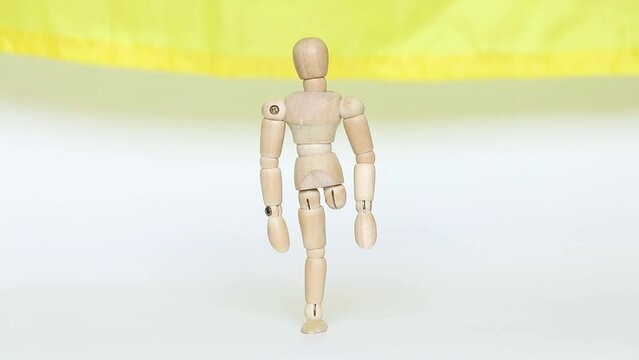 A wooden man without a leg against the background of the Ukrainian flag will lose his leg in the war