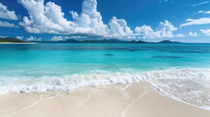 Obraz premium Soft white sand meeting turquoise water under a clear blue sky with fluffy white clouds