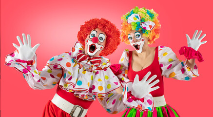 Surprised clowns, man and woman entertainers as Joker in a suit and wig, with clown whiteface makeup. Trickster, jester, pantomime, mime, and a professional actors at events, birthday party