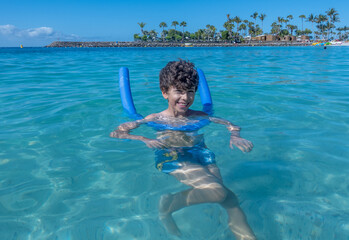 ni&ntilde;o nadando con flotador en la playa
