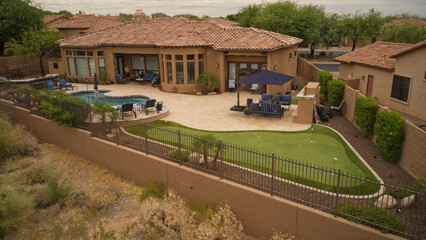 A Desert landscaped backyard in the American southwest featuring a travertine tiled patio pool, spa and outdoor kitchen.