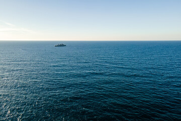 Aerial top view by drone of the sea with warship on horizon.